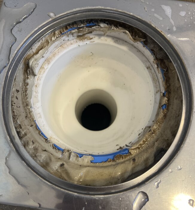 Golvbrunn med slitet tätskikt, synliga skador och löst material. Badrum från 2007, planerad renovering inom två år.