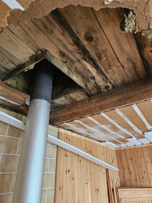 Rivet tak med synliga brädor och en rörledning, del av renovering efter tidigare vattenskada.