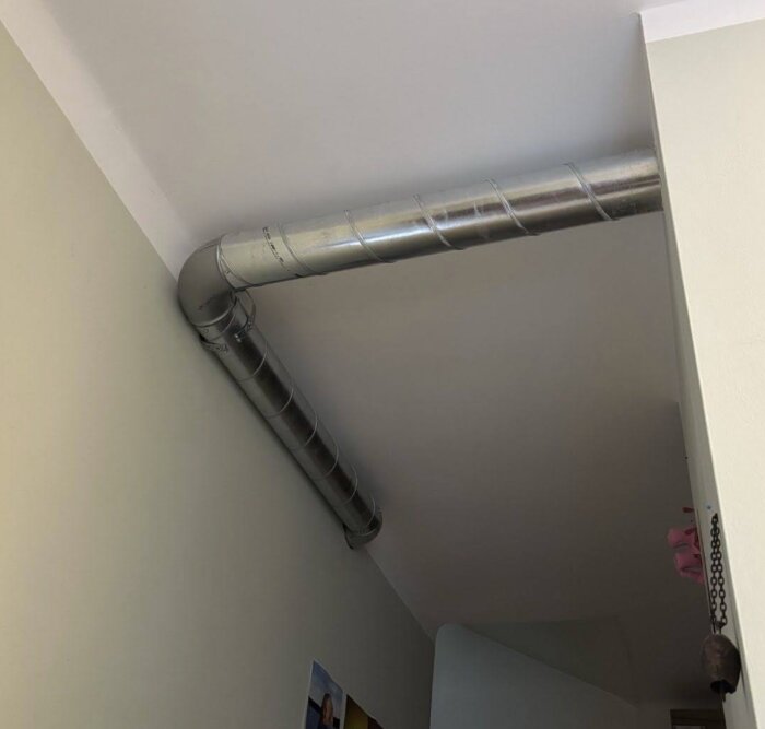 Exponerade ventilationsrör i ett hörn av ett rum med grå väggar och vit tak, installation efter FTX-system.