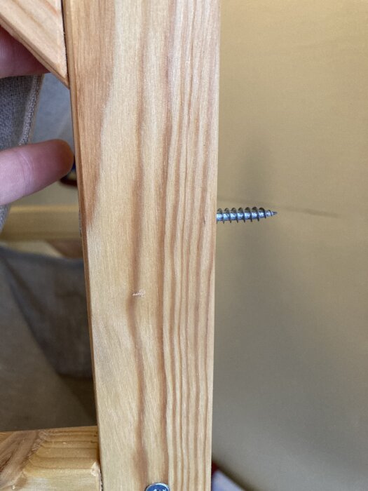 Skruv inskruvad i en träskiva, som är 10 mm tjock, med putsvägg bakom.