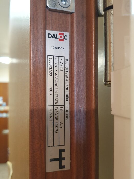 Etikett på dörrkarm med information om säkerhetsklass, brandklass och ljudklass från tillverkaren Daloc, tillsammans med tillverkningsnummer.