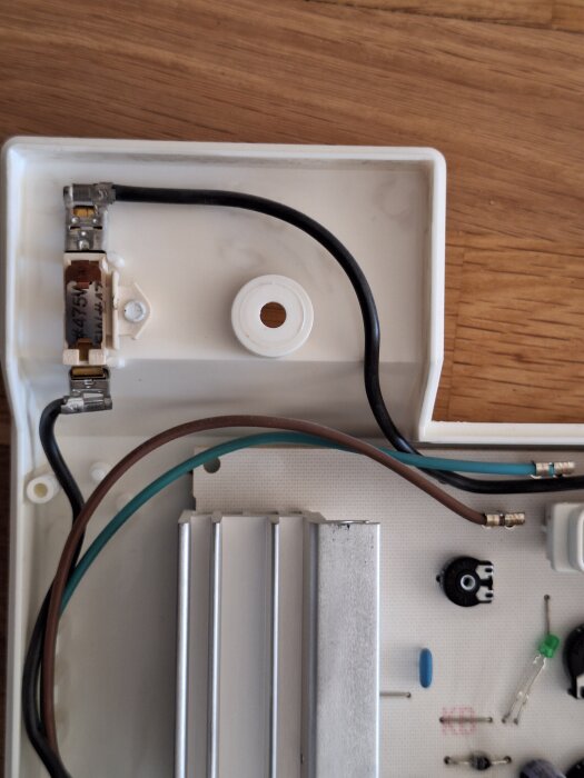 Närbild av kretskort med svart, brun och grön kabel anslutna, samt komponenter som potentiometer och kondensator på träram.
