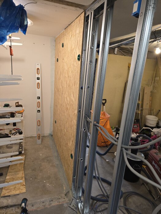 Monterade gipsskivor och stålskenor i ett rum under renovering, med verktyg och byggmaterial runtomkring.