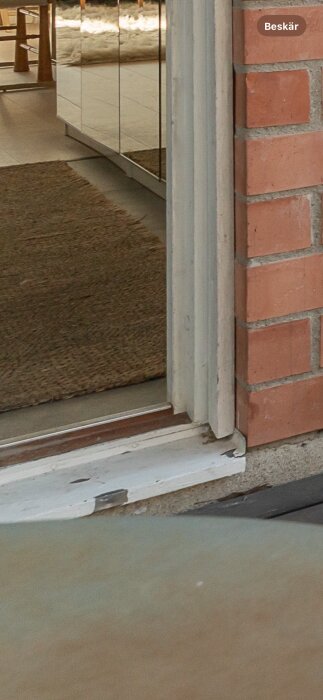 Glipa mellan dörrkarm och tegelvägg med borttagna träreglar, inuti modern interiör.