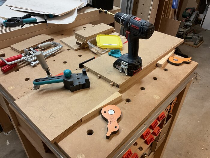 Verktygsbänk med borrmaskin, pluggjigg och andra snickarverktyg för sideboard-projekt i träverkstad.
