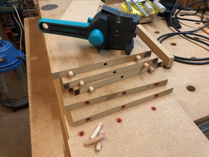 Träplugg och en Wolfcraft pluggjigg på arbetsbänk, med hyllplan och gavlar redo för montering, inlägg beskriver processen i detalj.