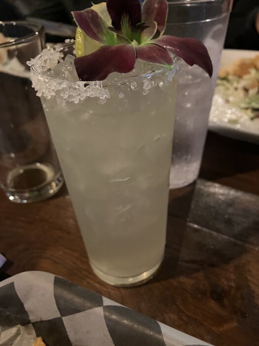 Margarita i glas med saltkant, dekorerad med en blomma och lime.