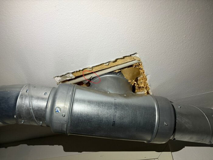 Avskuren kabel i tak med ventilationsrör i förgrunden, omgiven av gips och isolering; potential plats för skarvklämma synlig.