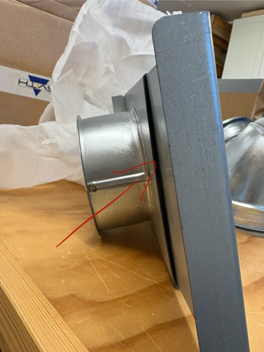 Närbild av en sugport med en ca 5 mm luftficka i öppet läge, markerad av en röd pil, på ett träbord.