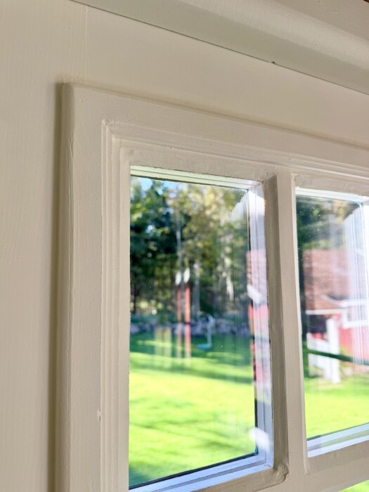 Närbild av glaspartier med kondens mellan bågarna på en verandadörr, omgivande trädgård syns utanför.