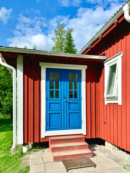 Rött trähus med blå dubbeldörr, vita knutar och trappa. Diskussion om luftning mellan bågar.
