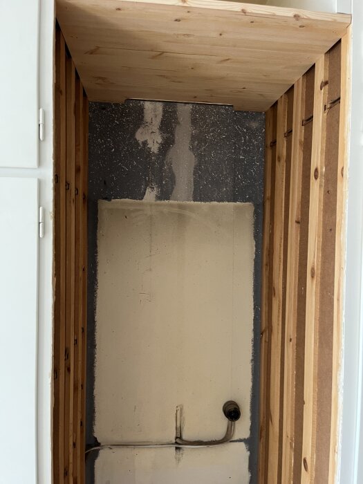 Utrymme för kyl/frys, byggt av två snickare på två timmar, med träpaneler och väggkonstruktion synlig.