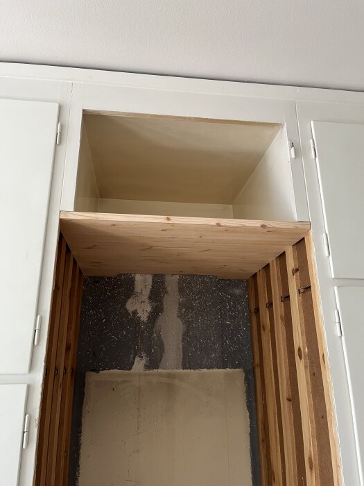 Öppning för kylskåp, träramar och hyllplan, redo för installation, byggt av snickare.