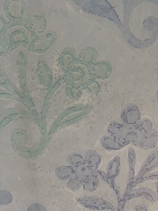 Blommig tapet med små svarta fläckar som kan indikera mögel i ett gammalt hus.