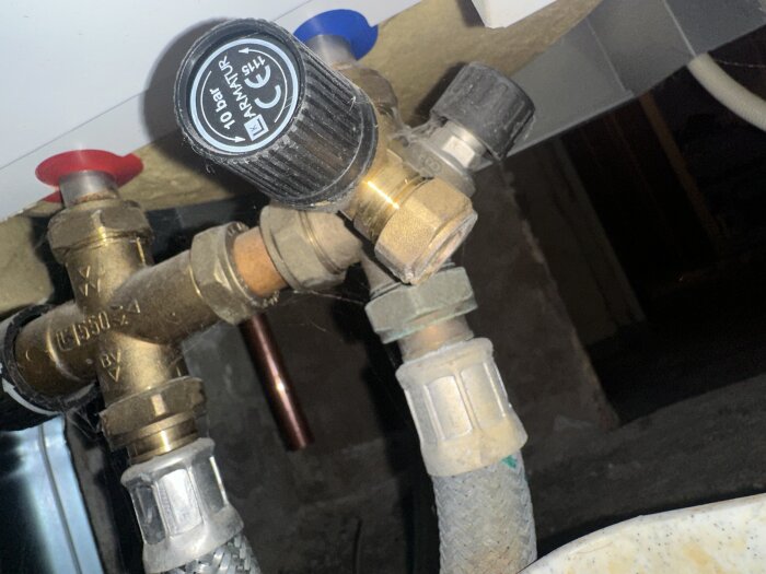 En vattenventil med mässingskopplingar och svart vred. Märkt för 10 bar av ett varumärke. En blå och röd markör syns i bilden.