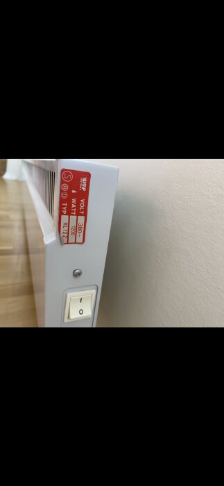 Vitt element med märkning "380 volt" och "1200 watt", samt en vit strömbrytare monterad på framsidan.