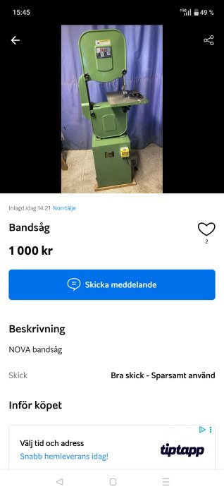 Grön bandsåg märkt "Nova" står på golv framför ett blått draperi.