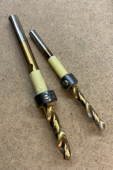 Dubbla borr med djupstopp i metall och plast, placerade på en träyta för träpluggar enligt inlägg om borrjiggar och djupstopp från Wolfcraft.