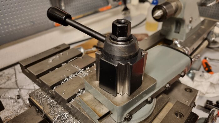 Verktygshållare med snabbfäste monterad på en svarv, omgiven av metallspån.