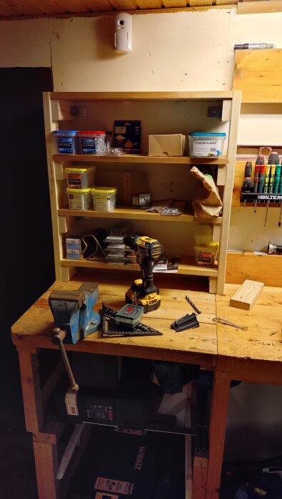 Hemmabyggd hylla av spillvirke på en arbetsbänk, fylld med verktyg och förvaringslådor för bättre ordning.