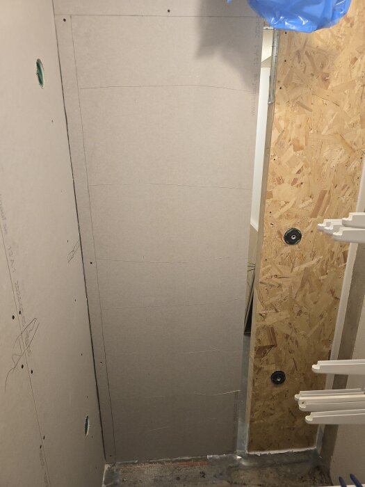 Gipsväggar uppsatta i klädkammare med eldosor synliga, träpanel syns på sidan, förbereder för belysning och ventilation.