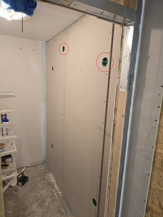 En klädkammare under renovering med monterade gipsväggar, synliga ventilationsrör och två markerade nätverksuttag.
