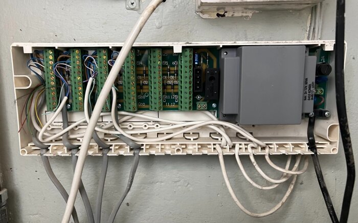 En reglercentral med flera styrdon och kablar anslutna i en väggmonterad enhet.