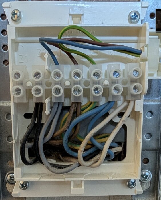 Elcentral med kopplingsklämmor och olika färgade kablar monterade på en vägg.