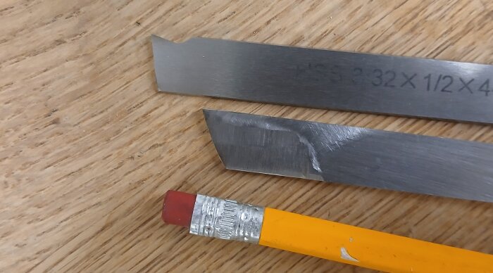 Två metallstänger, övre för stål/alu och undre för mässing/brons, med en penna bredvid, på en träyta.