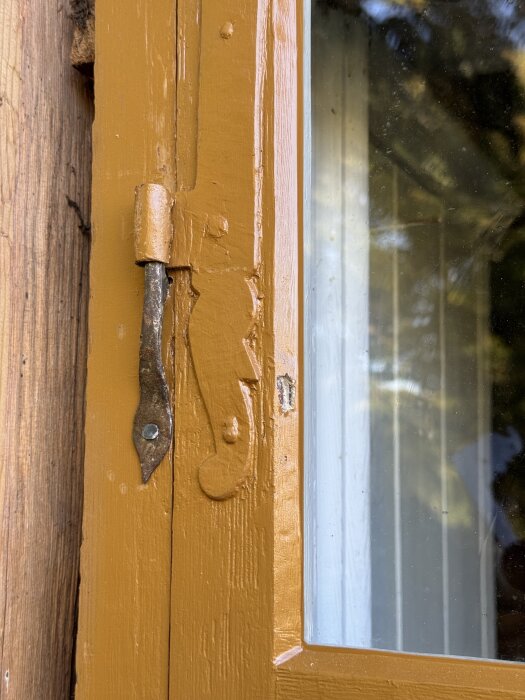 Gult fönster med kittskada på träkarmen, orsakad av fågelaktivitet.