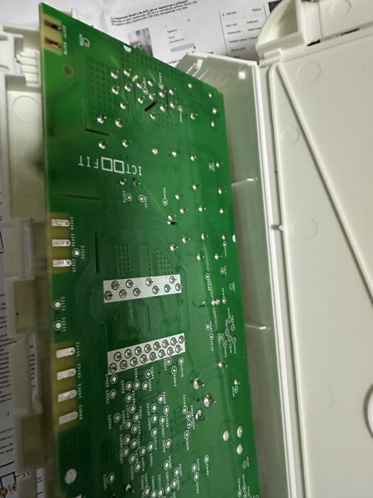 Kretskort från en Electrolux-diskmaskin med en svart/bränd fläck nära den gula komponenten märkt TVR 14471, ligger i en vit hölje.