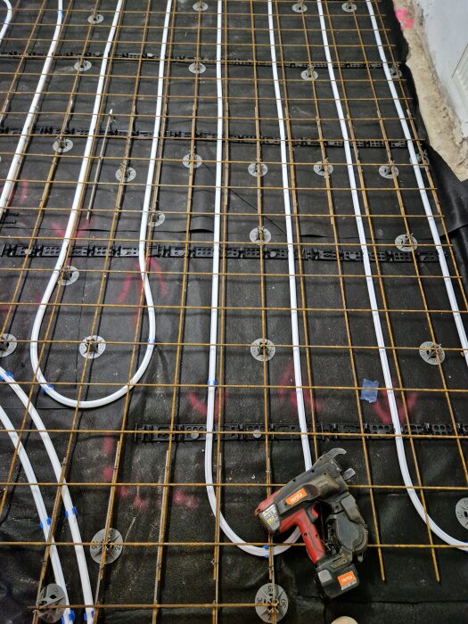Installation av golvvärmerör med armeringsjärn och ett verktyg av märket Renta på golvet.