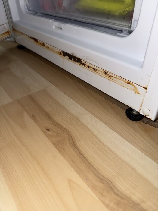 Rostskada på botten av en Whirlpool kylskåpsdörr med frost och läckageproblem.