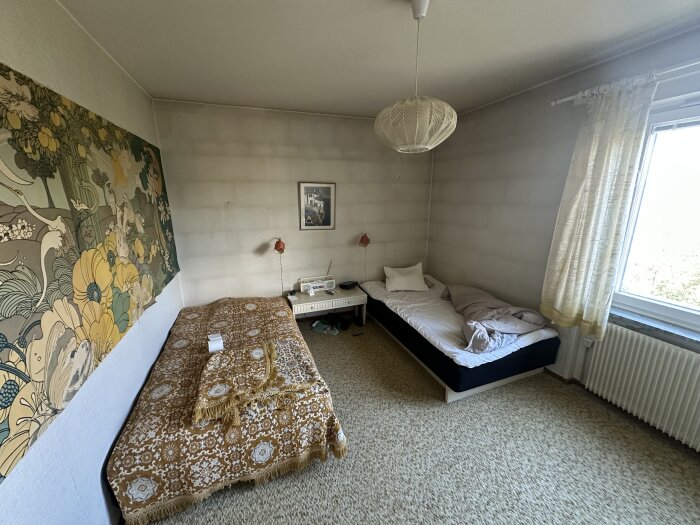 Sovrum med mönstrad tapet, två sängar och synliga skarvar i väggarna, som matchar murstenar. Vintage stil med blomdetaljer på väggen.