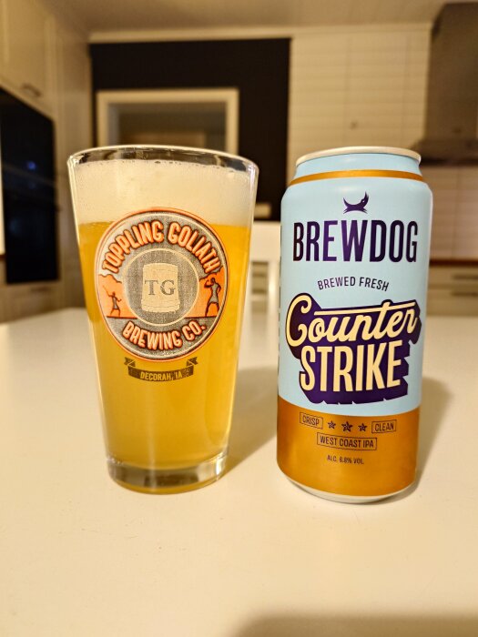Ett glas öl från Toppling Goliath och en burk Brewdog Counter Strike West Coast IPA på ett bord i kökets inredning.