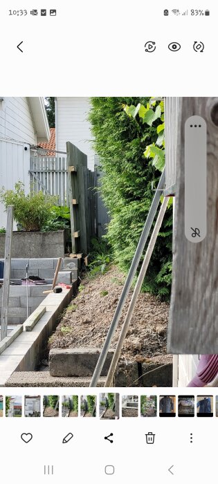 Dike med öppen jord och lutande staket vid bostadstomt. Muren sänkt av grannar, vilket skapat en slänt och dike utan stödvägg.