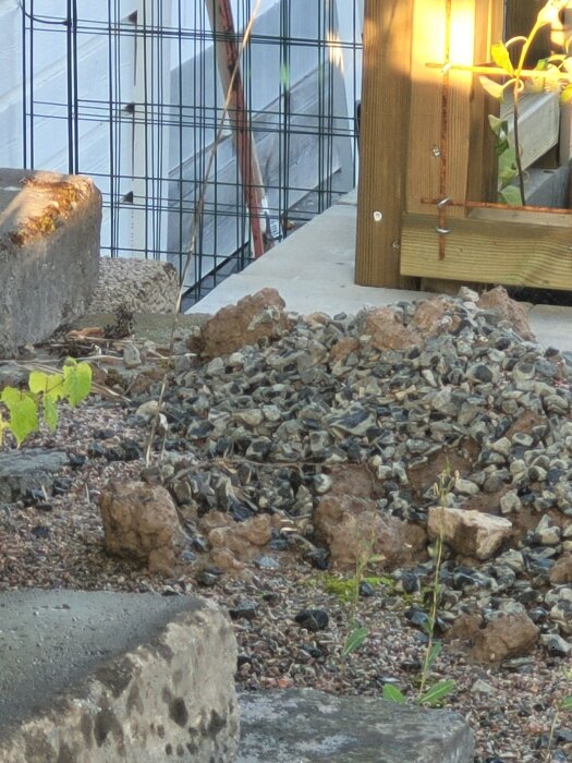 Grus- och stenfylld markyta med ojämnheter, gränsad av betongblock och ett trästaket i bakgrunden, del av en konflikt mellan tomtägare.