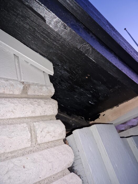 Närbild på takfotsbrädor och tak, med målade ytor och en skarv mellan tak och vägg på en villa.