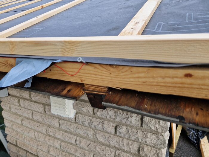 Nyinstallerat tak med träreglar och diffusionsduk, visar takfot och plåt på 70-talsvilla.