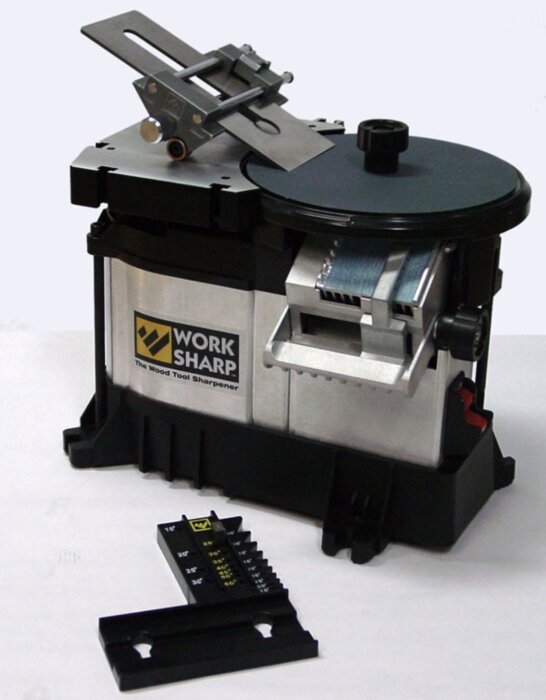 Work Sharp verktygsslip med extrabord och bryningsjigg ovanpå, vid sidan ligger en vinkelguide för slipning.