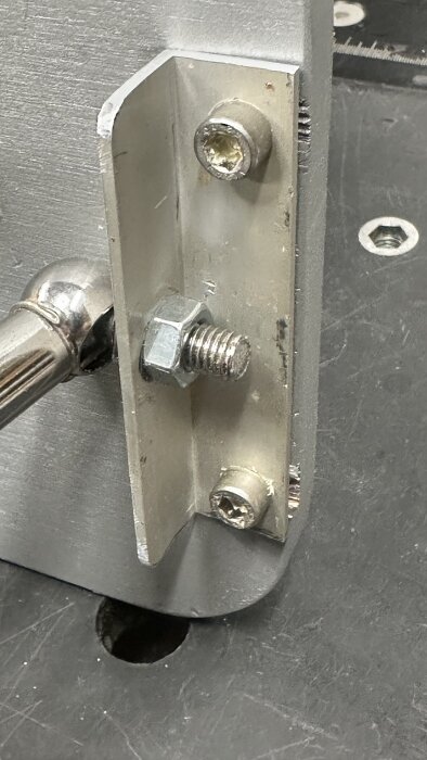 Närbild av en monteringsdel på ett extrabord, med metallplatta och skruvar, från ett slipmaskinsprojekt enligt beskrivning.