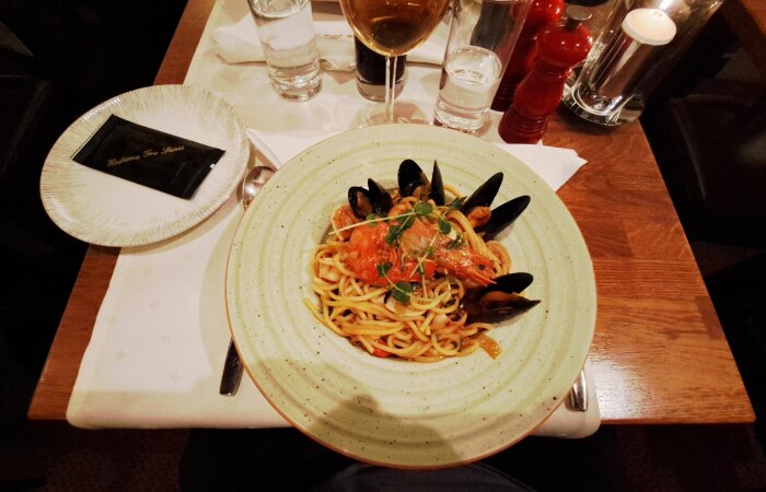 Pasta med skaldjur, inklusive musslor och räka, serverad på en tallrik.