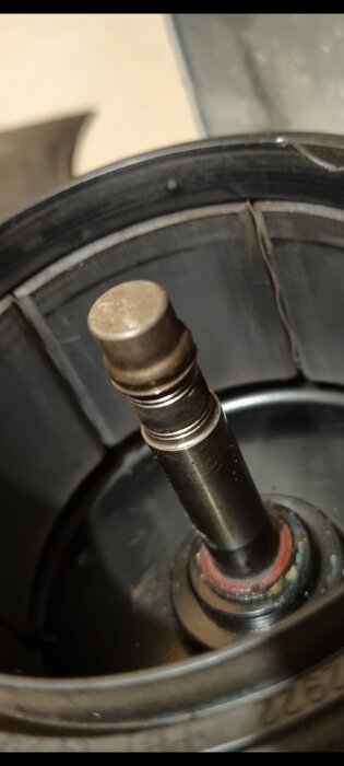 Fläktaxel med synlig skade på speedy sleeve, trasig hylsa och smuts. Potentiellt reparationsbehov för renovering av fläktsystem.