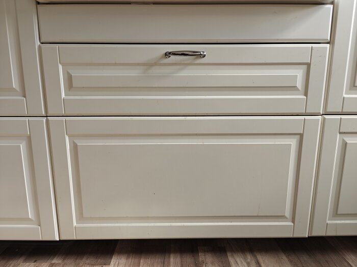 Vit kökslåda från Ikea som sitter snett, med vänster sida närmare skåpskanten. Problem med sopsorteringslådans justering syns tydligt.