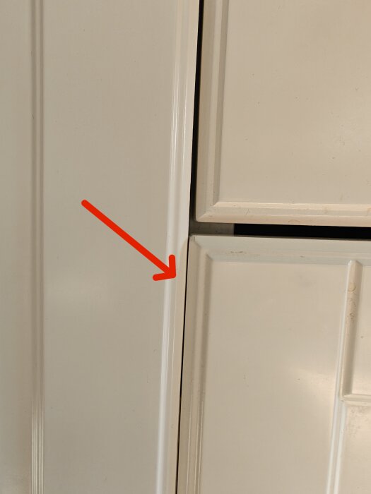 Sopskåpslucka som sitter snett i ett Ikea-kök, med synlig glipa på vänstersidan och en röd pil som pekar mot felet.