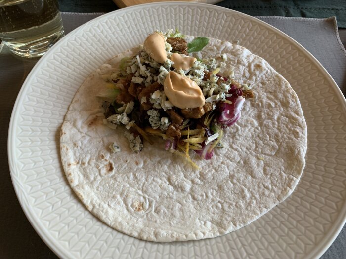 Wrap med shawarma-kryddad karré, blandsallad, strimlade morötter i olika färger, och sås på fat.