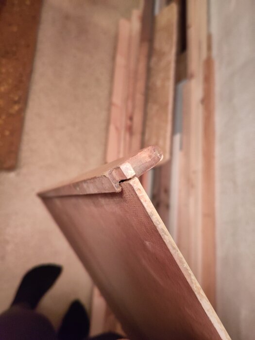 En närbild av kanten på en trädörr med en list på ena sidan, omgiven av träbrädor.