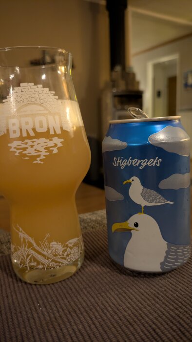 Ölglas med logga och burk med illustration av två fiskmåsar och texten "Stigbergets".