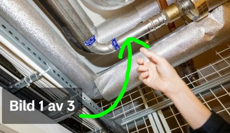 Hand pekar på en tappvatteninstallation med rostfria rör.