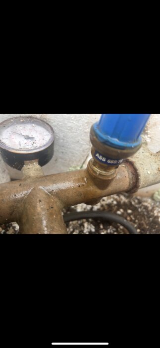 Manometer och blå komponent märkt "ASS 689" på kopparrör i ett vattensystem.